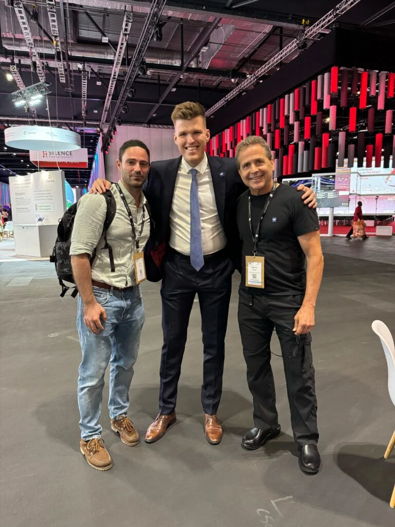 Three men posing together in the exhibition hall at ESC Congress 2024 in London