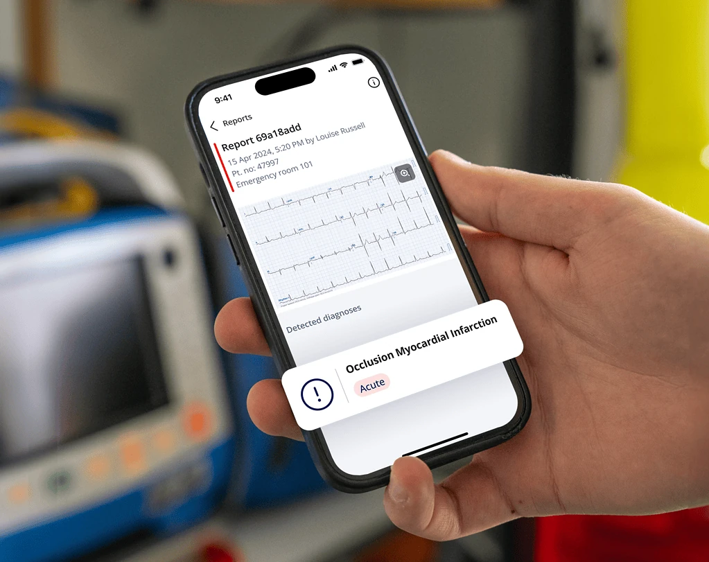 Clinician holding phone in an ambulance showing PMcardio report flagging acute Occlusion Myocardial Infarction