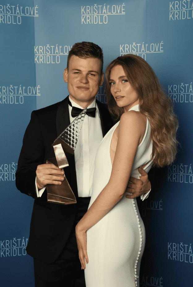 Martin Herman holding Crystal Wing trophy beside his partner at the Kristalove Kridlo backdrop