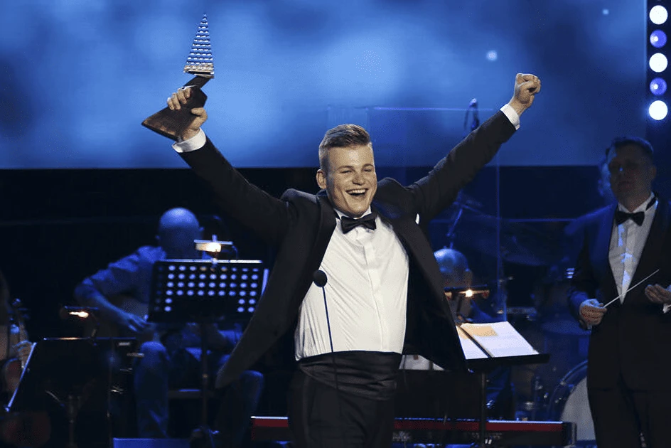 Martin Herman raising Crystal Wing Award trophy triumphantly on stage at the awards ceremony
