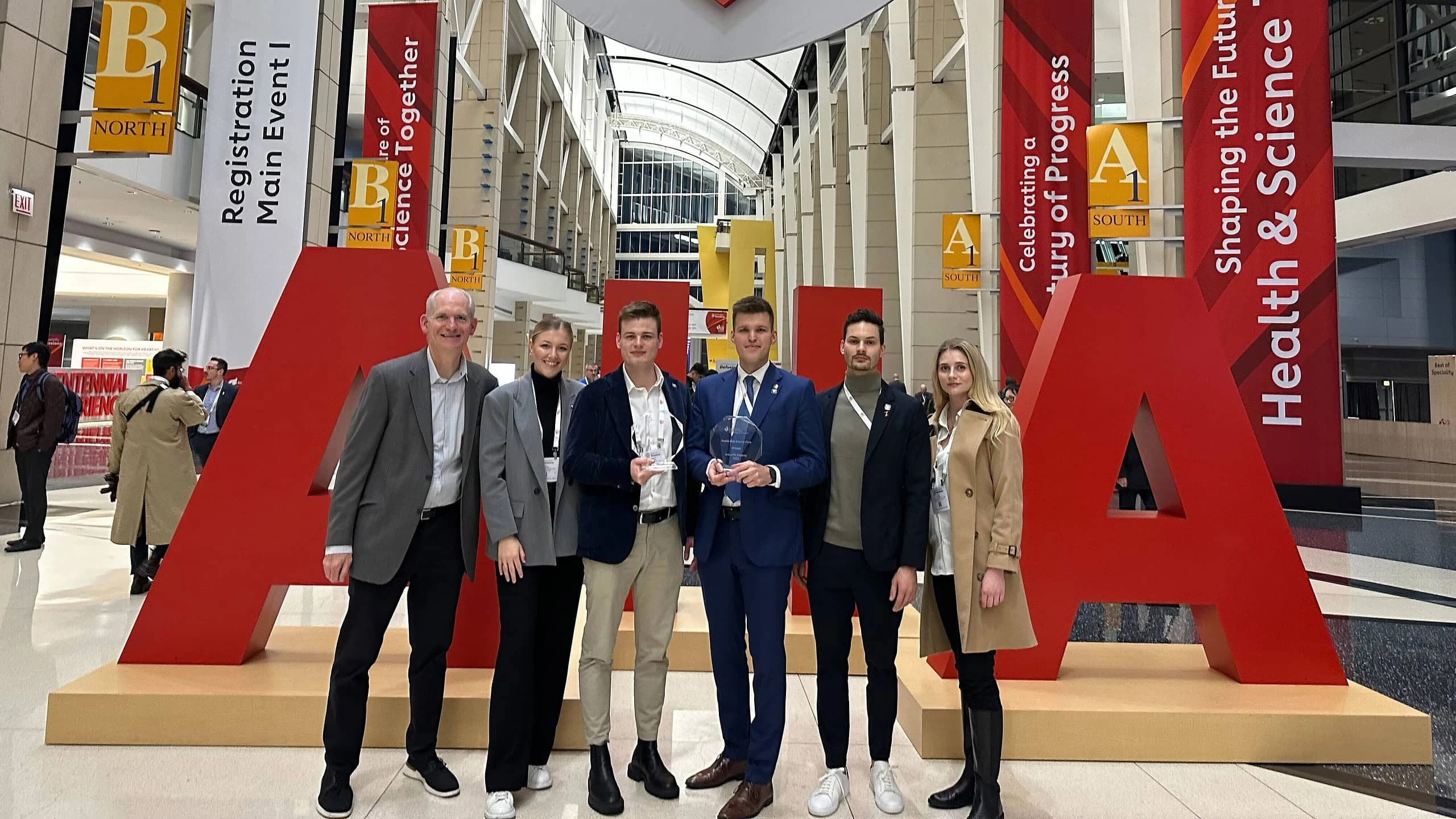 Powerful Medical team holding their awards beside giant red AHA letters at the 2024 Scientific Sessions