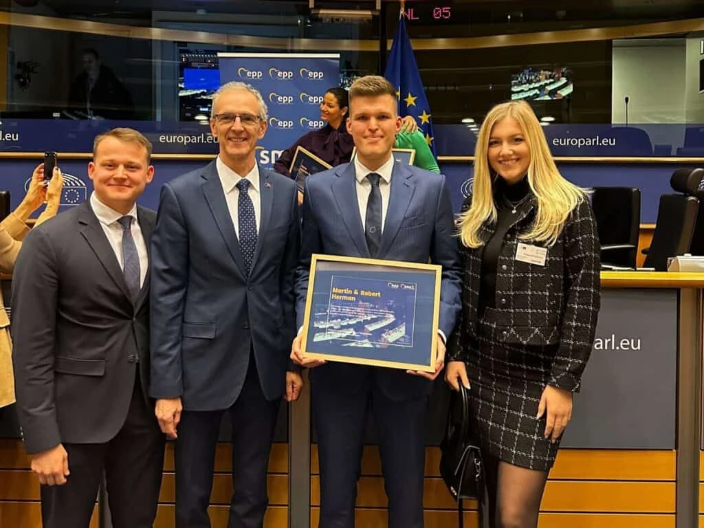 Robert Herman holding the framed SME Europe Award between two officials at the European Parliament in Brussels