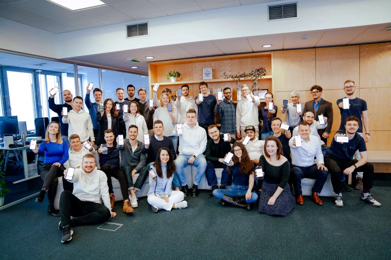Powerful Medical team celebrating the PMcardio app launch, holding phones running the app in their office
