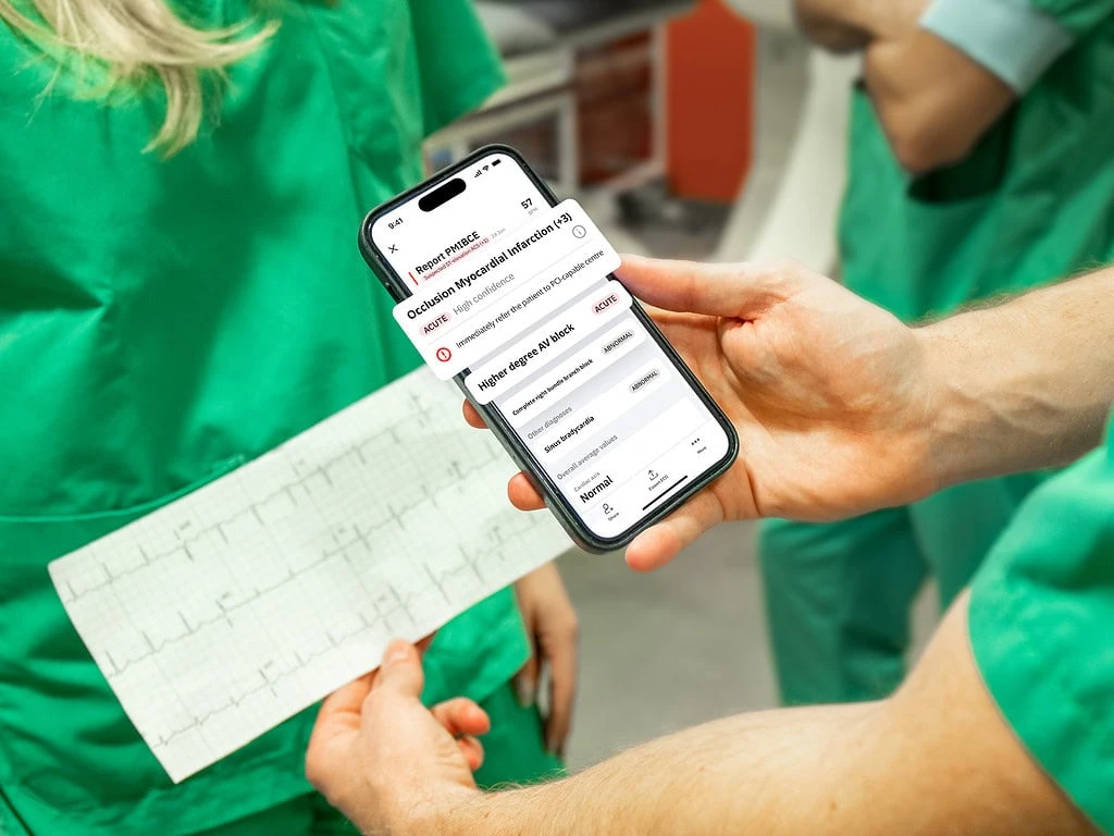 Clinicians reviewing a printed ECG and PMcardio smartphone report flagging acute Occlusion Myocardial Infarction