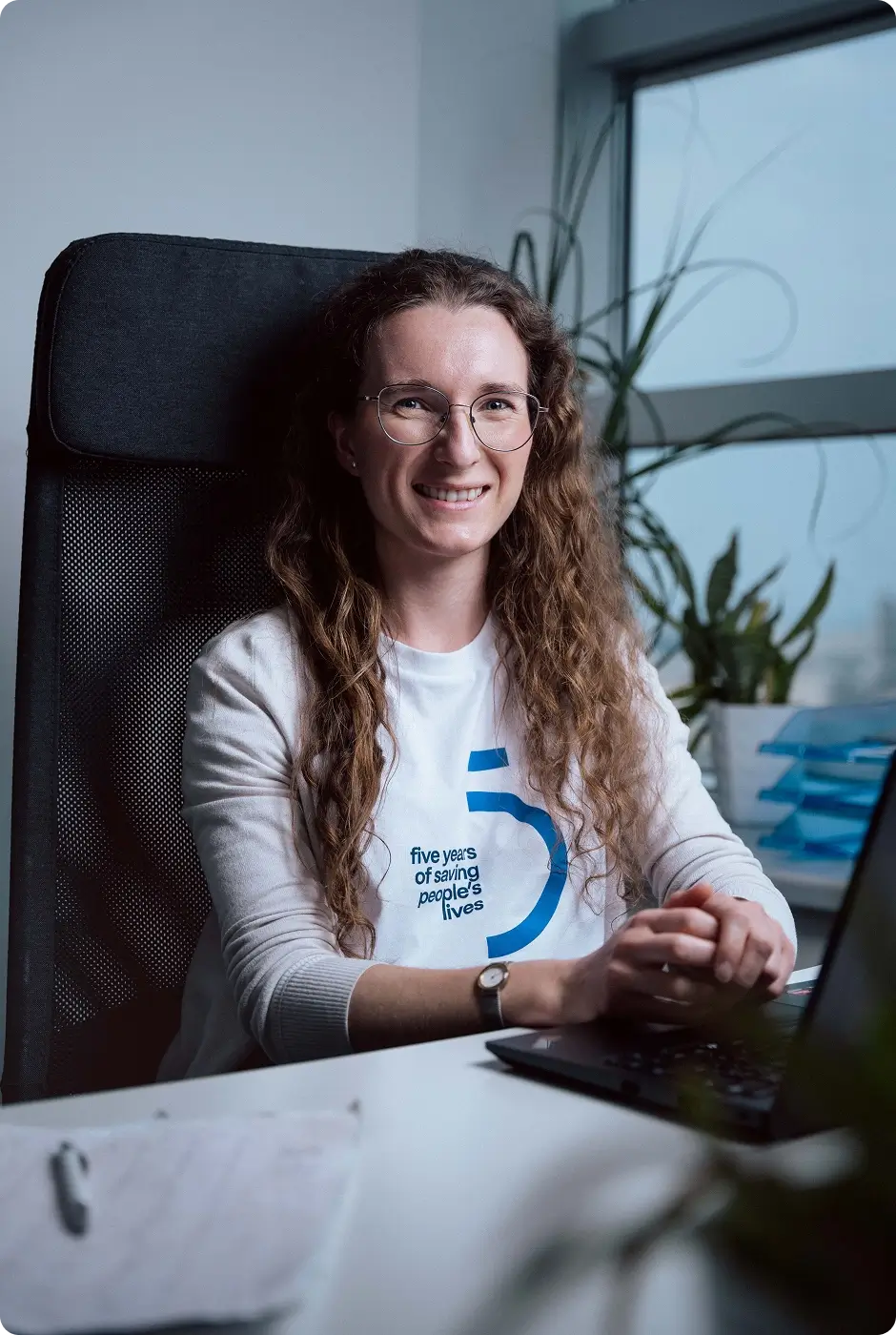 Daniela Sitarova, Product Operations Manager at Powerful Medical, at her desk in a five-years anniversary t-shirt