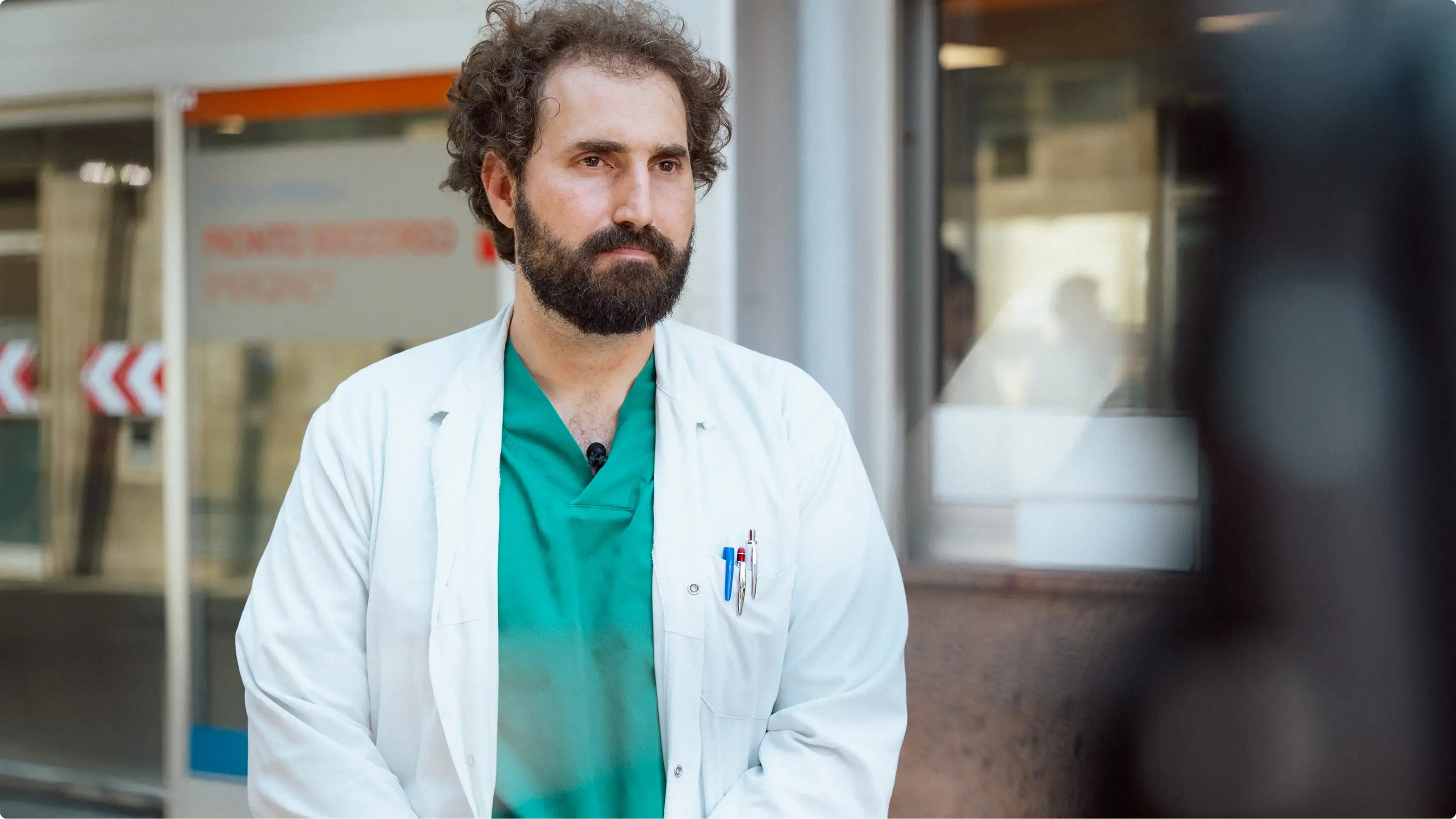 Clinician in a white coat and green scrubs outside the Sant'Andrea emergency department, still from the Inside Sant'Andrea's AI-Powered STEMI Pathway film