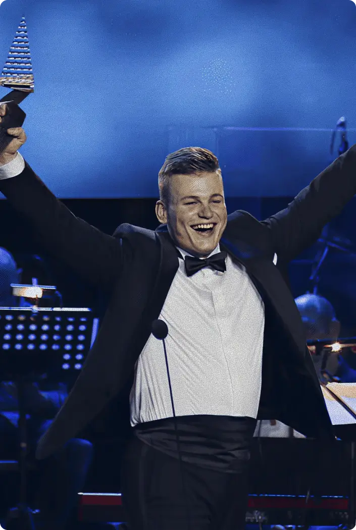 Martin Herman in a tuxedo raising the Crystal Wing Award on stage