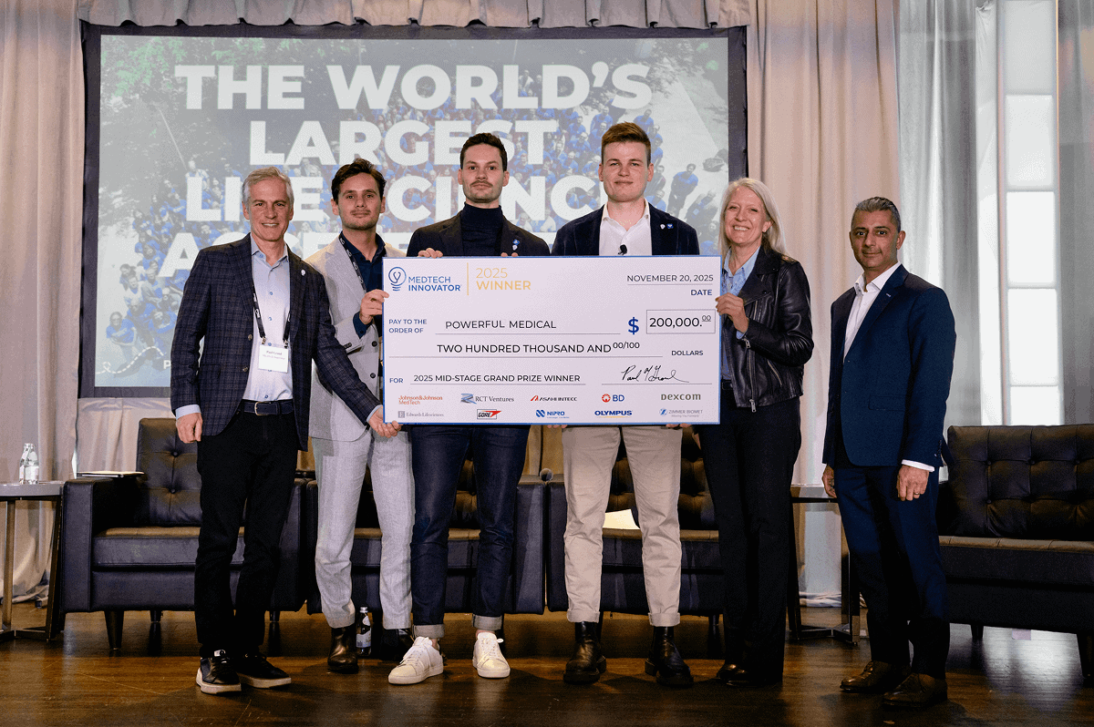 Powerful Medical team receiving the MedTech Innovator 2025 Mid-Stage Grand Prize award on stage, holding a large winner’s check.